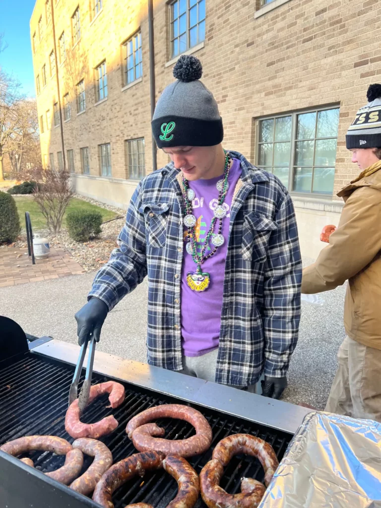 A Griffin grills some andouille sausage in preparation for Mardi Scraw